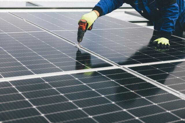 Worker installing solar panels on a rooftop.